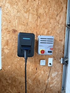 Borne de recharge Hager witty installée par Eilan dans un garage, câble branché et voyant de charge allumé